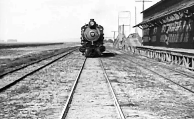 a black and white photo looking straight down tracks to the front of a locomotive