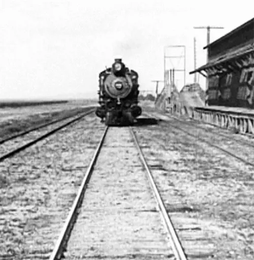 a black and white photo looking straight down tracks to the front of a locomotive