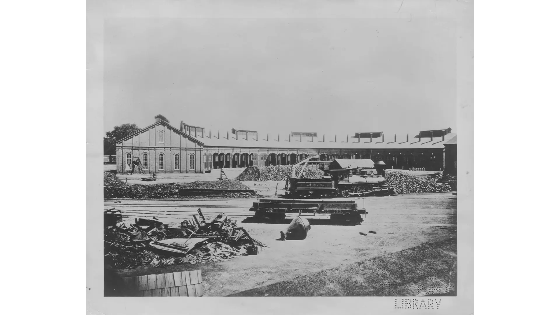 a black and white photo of a train locomotive roundhouse