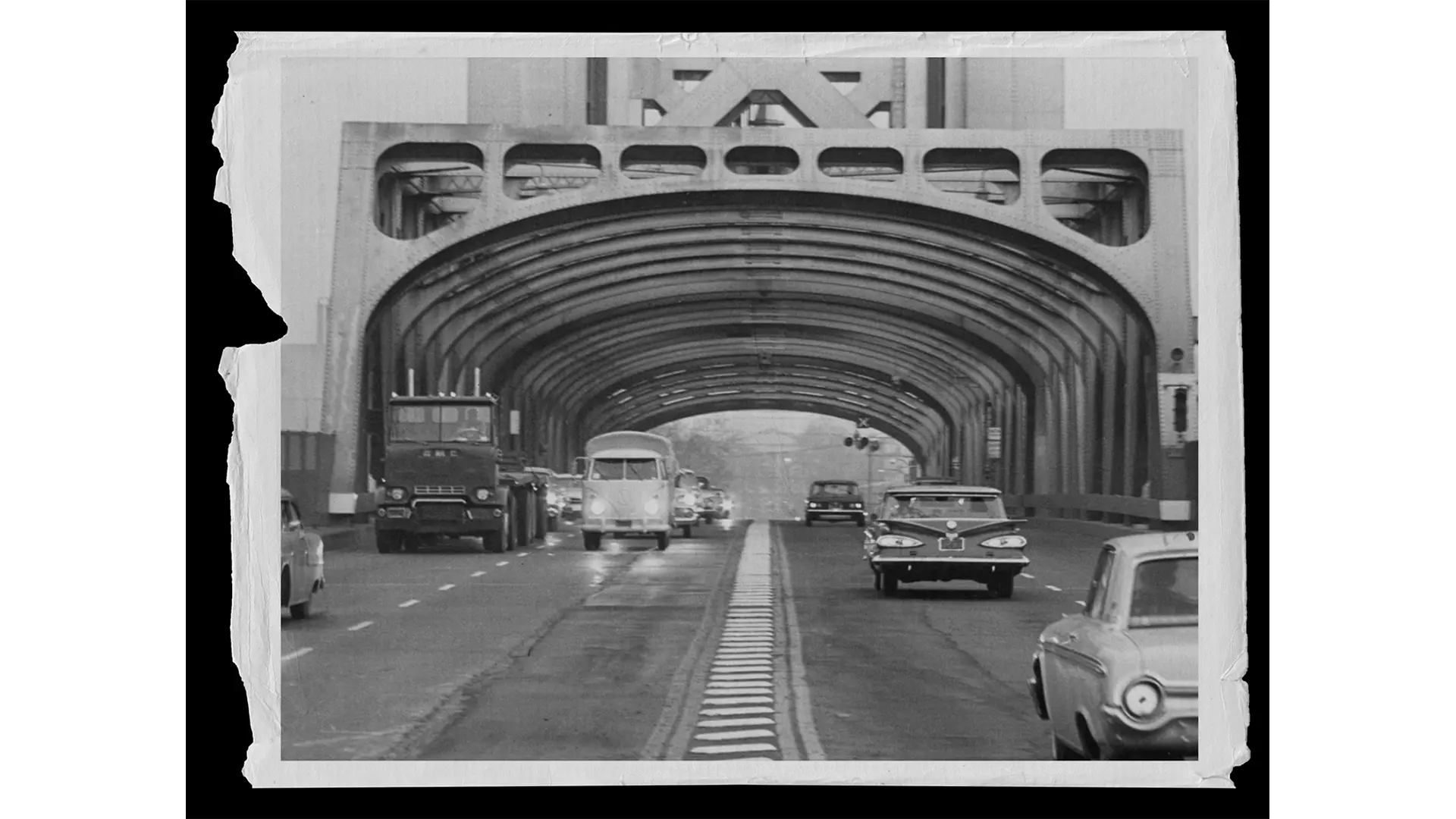 a black and white photo of cars driving over a bridge