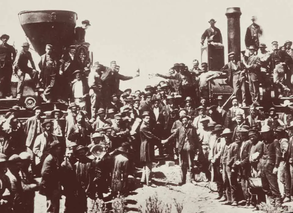 a black and white photo of two locomotives with many men around and on them
