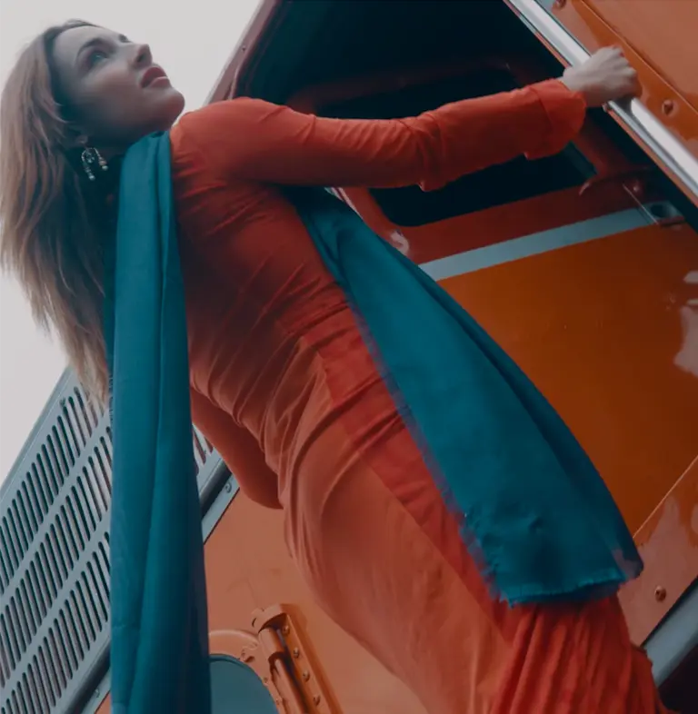 a woman in a red dress leaning out the door of a red locomotive