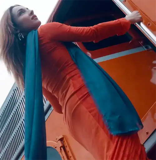 a woman in a red dress leaning out the door of a red locomotive