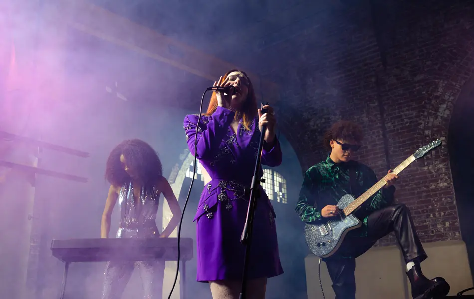 A band of three people playing music in a brick building