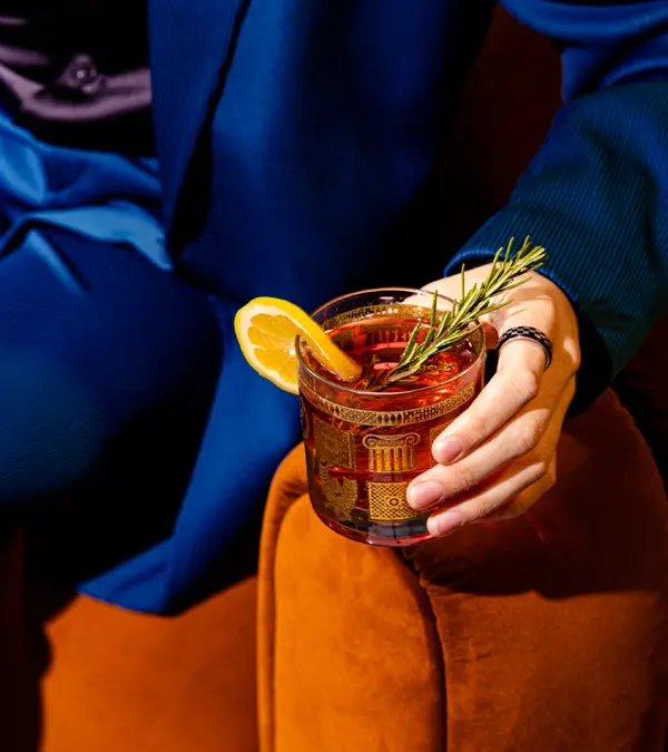 a close up image of a cocktail drink held in a man's hand