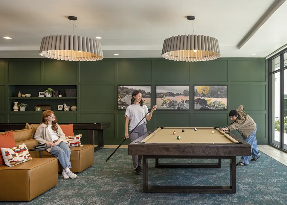 a man and woman playing pool with another woman watching in the lounge at the AJ