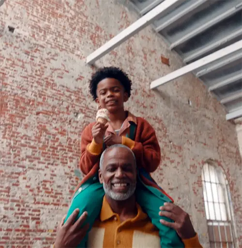 a photo of an elderly man holding a young boy with an ice cream cone on his shoulders