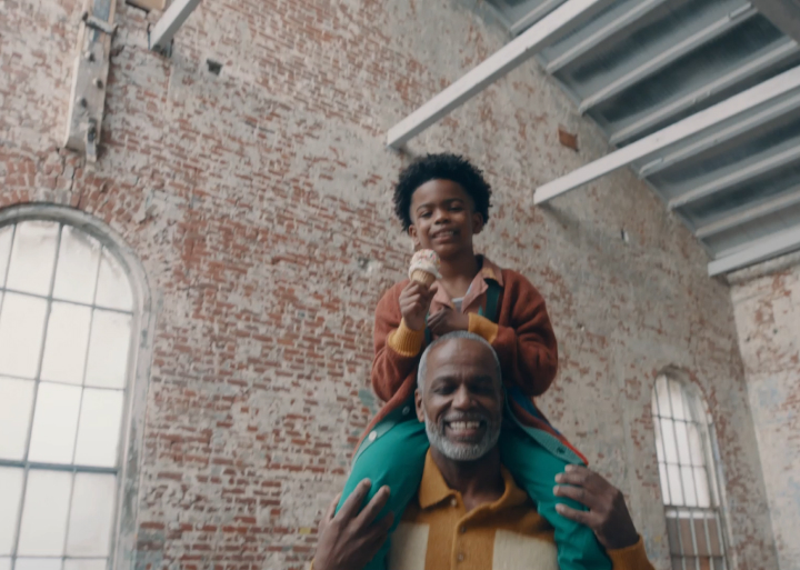 a photo of an elderly man holding a young boy with an ice cream cone on his shoulders