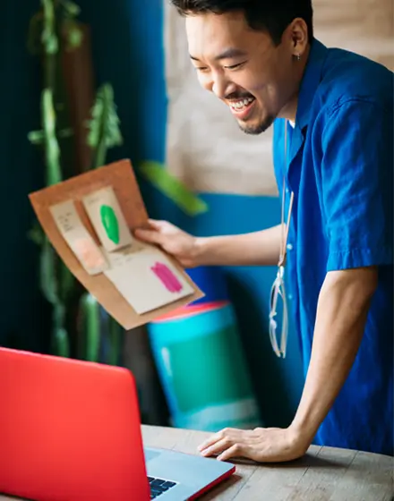 a photo of a happy man holding a documment while looking at his computer