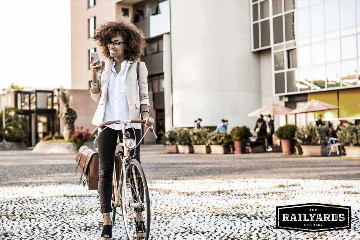 A woman on a bicycle checking her phone. Learn more about how Sacramento is celebraing bike month.